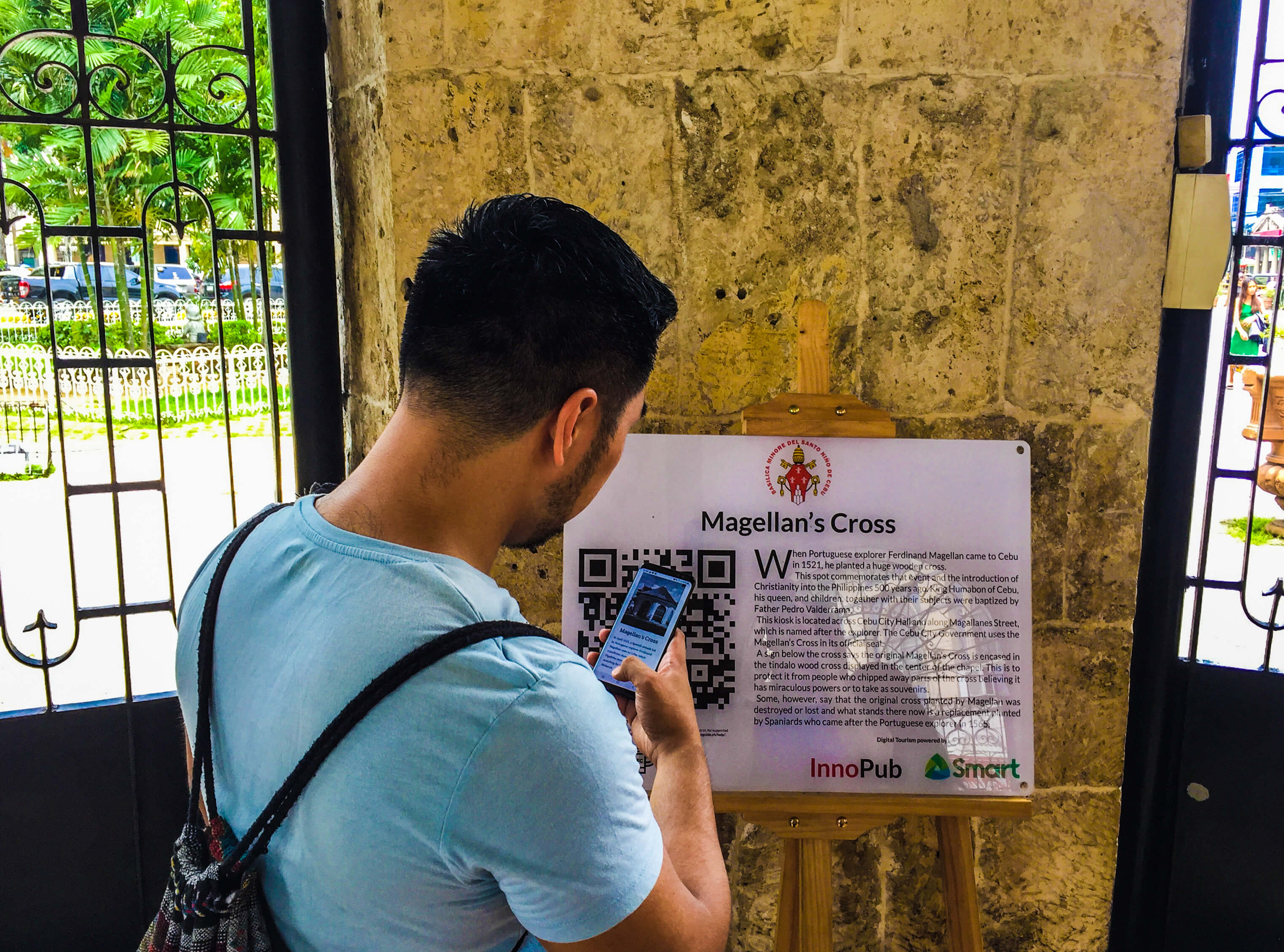 MAGELLAN’S CROSS. A visitor reads about the history of the Magellan’s Cross and views archival photos of the kiosk after scanning the interactive Digital Tourism marker placed there.